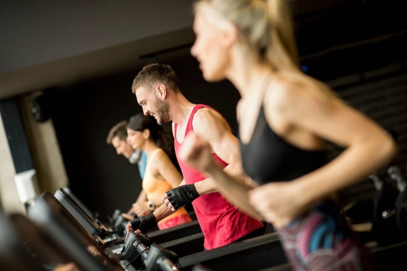 Group of young people running on treadmills in modern gym